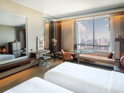 Modernes Hotelzimmer mit zwei Betten, großem Fenster mit Stadtblick und elegantem Interieur.