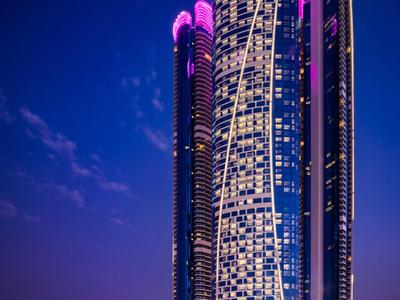 Rascacielos moderno con iluminación LED morada y blanca por la noche