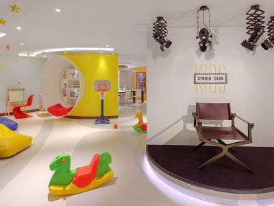 Área de juegos moderna para niños en hotel con pufs coloridos, juguetes y diseño creativo.