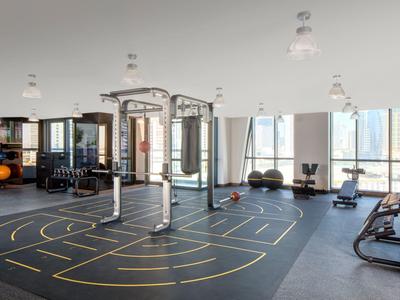 Gimnasio moderno con equipos de entrenamiento y grandes ventanas con vistas a la ciudad.