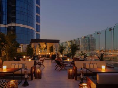 Elegante terraza en la azotea con áreas de descanso y luz cálida por la noche en un hotel.