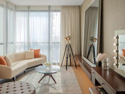 Sala moderna con sofá, mesa de vidrio y ventana grande con cortinas.