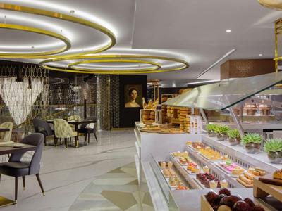 Café moderno con interior elegante y un buffet con varios pasteles y sándwiches.