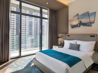 Modern hotel room with large window and city view, comfortable bed, and stylish decor.