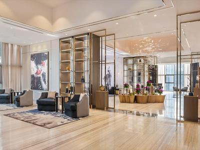 Moderní interiér hotelové lobby se sezením, velkými okny a elegantní dřevěnou výzdobou.