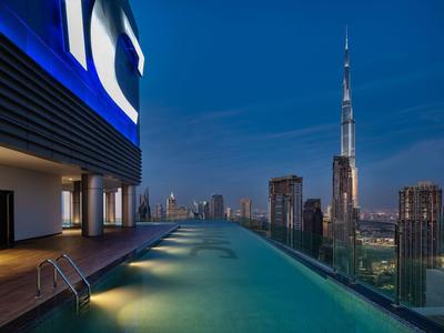 Infinity-Pool auf Dachterrasse mit Blick auf die beleuchtete Skyline und Burj Khalifa bei Nacht.