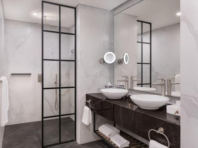 Modern bathroom with double sinks and black glass door to the shower.