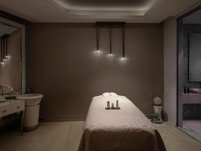 Moderne spa behandelruimte met massagetafel, gedimd licht en rustgevende sfeer.