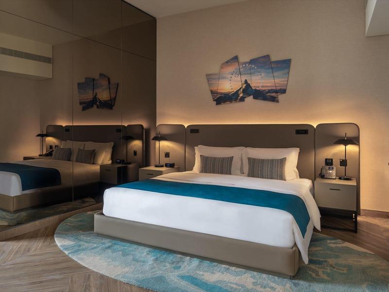 Modern hotel room with double bed, nightstands, lamps, and maritime wall decoration.