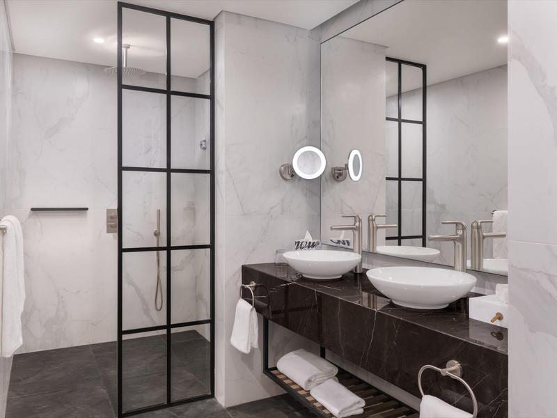 Modern bathroom with double sinks and black glass door to the shower.