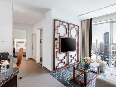 Moderne hotelkamer met zithoek, bureau en groot raam met uitzicht op de stad.