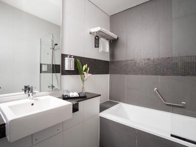 Moderne badkamer met wastafel, bad en grijze tegels