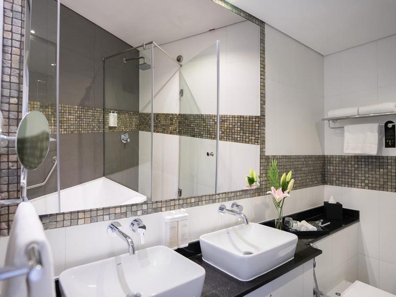 Moderne badkamer met dubbele wastafels, spiegelwand en zwarte werkbladen