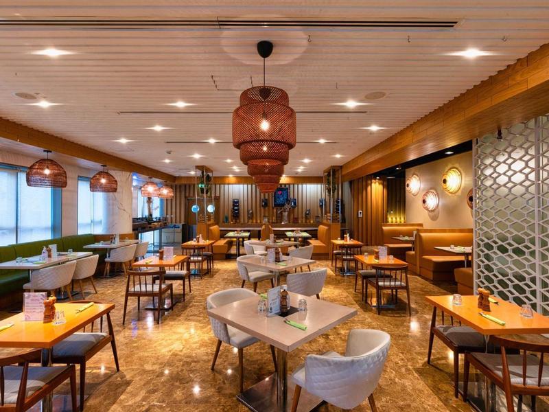 Moderne restaurantruimte met houten meubels, ronde lampen en een gezellige sfeer.
