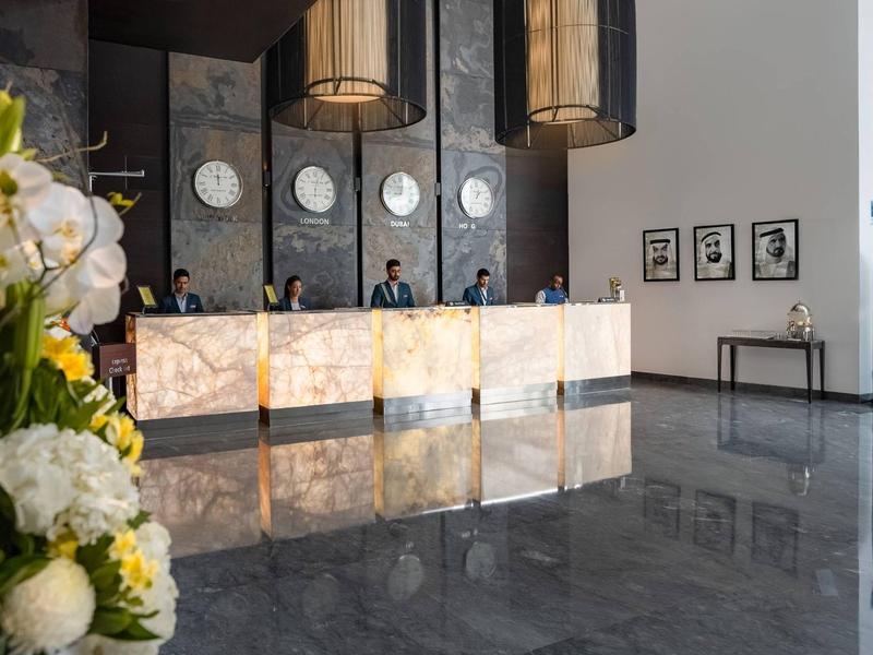 Moderne hotelreceptie met verlichte marmeren balie en decoratieve lampen.