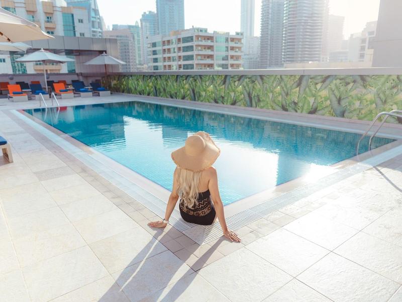Vrouw met zonnesteek zittend aan de rand van een zwembad in een stedelijk hotel.