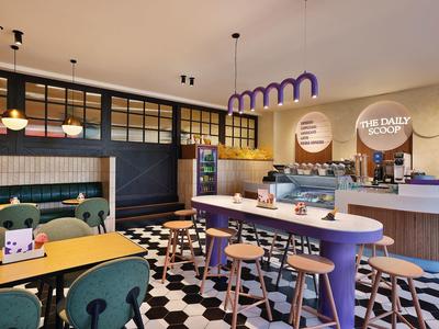 Salle de petit-déjeuner moderne avec mobilier coloré et sol carrelé noir et blanc.