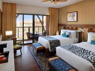 Une chambre d'hôtel moderne avec deux lits, balcon et vue sur l'eau et le pont.