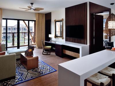 Chambre d'hôtel accueillante avec balcon, canapé, tapis et mobilier moderne.