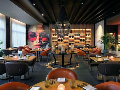 Restaurant élégant au design moderne, tables rondes et art mural coloré.