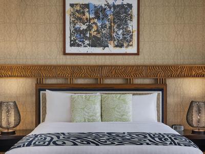 Chambre d'hôtel moderne avec grand lit double, coussins décoratifs et lampes de chevet élégantes.