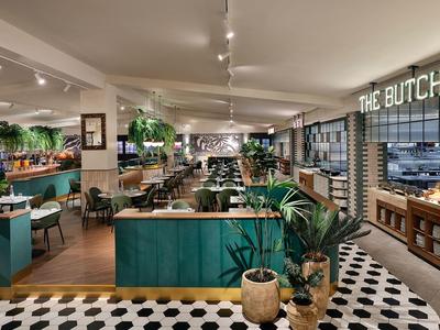 Modern restaurant with green booths and plants, cozy atmosphere.