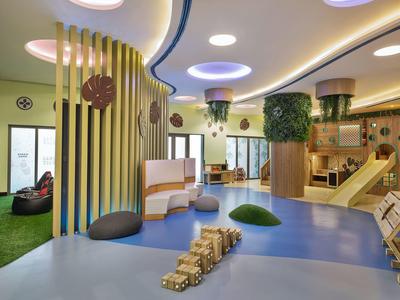 Espace de jeu intérieur moderne et lumineuse avec toboggans et sièges aux couleurs chaudes.