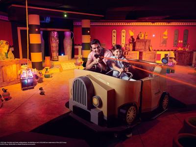 Play area with themed vehicles and adults playing in a warmly lit room