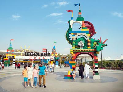 Entrance to LEGOLAND with a colorful LEGO structure and visitors under clear sky.