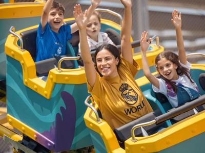 Three people raising their arms and laughing in a roller coaster car