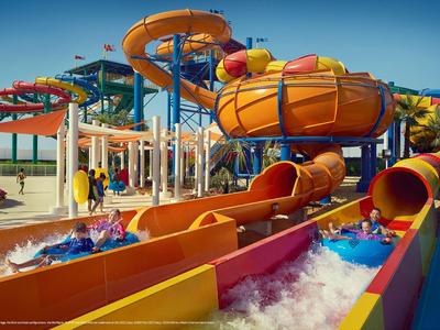 Colorful water slides in a water park with people on rafts in the flowing water.