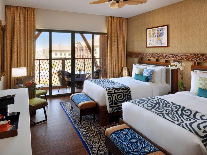 Une chambre d'hôtel moderne avec deux lits, balcon et vue sur l'eau et le pont.