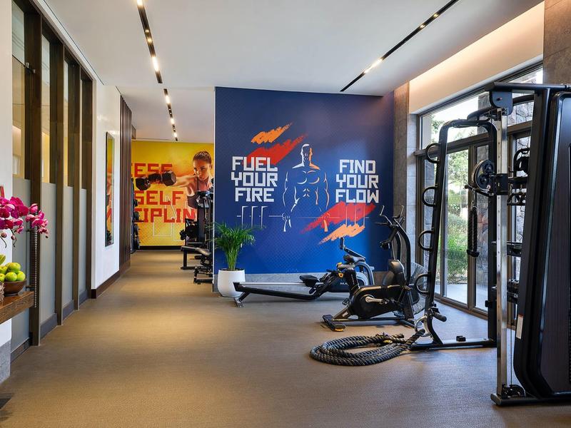 Salle de sport moderne avec équipements, citations motivantes sur les murs et grandes fenêtres.