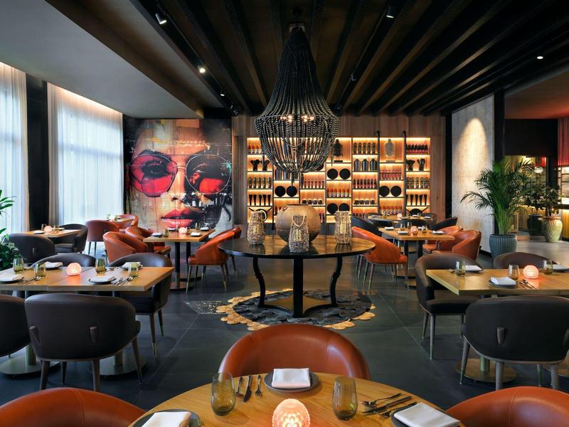 Restaurant élégant au design moderne, tables rondes et art mural coloré.