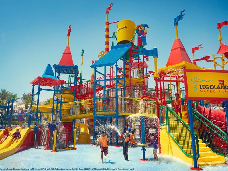 Aire de jeux aquatique colorée avec toboggans et seaux dans un parc d'attractions Legoland.
