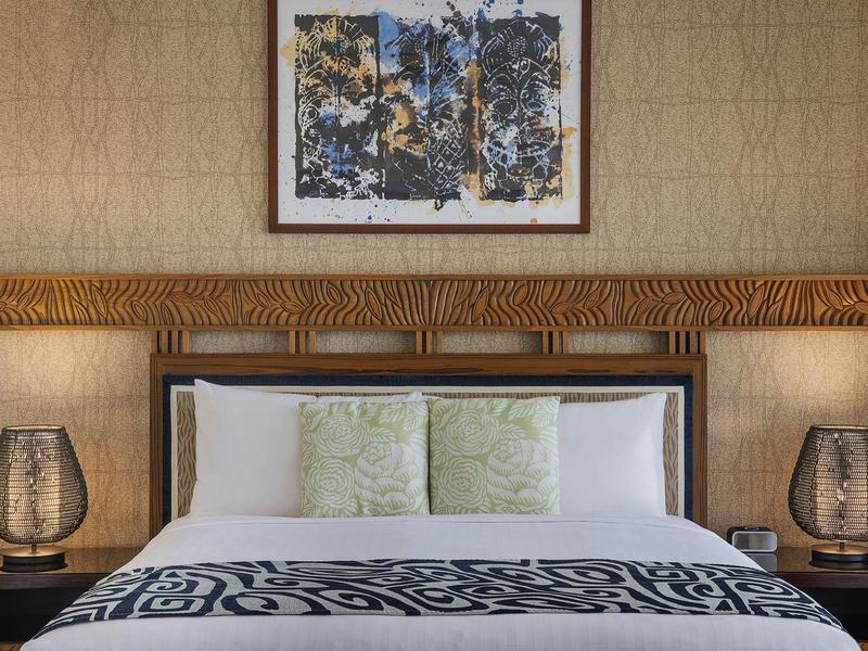 Chambre d'hôtel moderne avec grand lit double, coussins décoratifs et lampes de chevet élégantes.