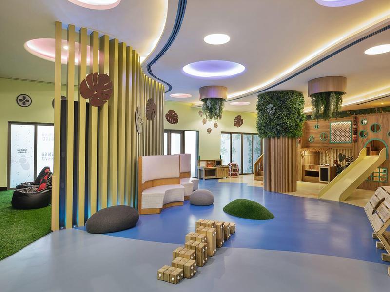 Espace de jeu intérieur moderne et lumineuse avec toboggans et sièges aux couleurs chaudes.