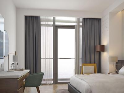 Modernes Hotelzimmer mit Doppelbett, Balkonfenster und Schreibtisch mit Stuhl.