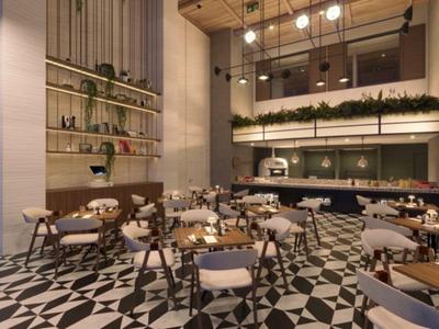 Helles, modernes Hotelrestaurant mit geometrischem Bodenmuster und gemütlichen Sitzbereichen.