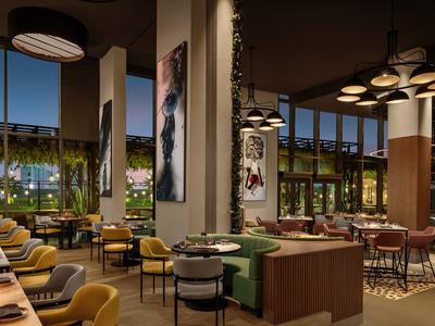 Elegantní hotelová restaurace s prostornými sedačkami, moderním osvětlením a velkými okny.