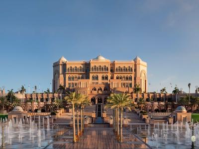 Luxuriöses Hotel mit Palmen und Wasserfontänen unter klarem Himmel