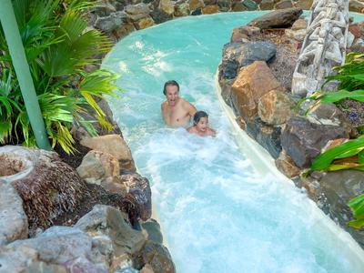 Zwei Personen rutschen in einem von Felsen umgebenen Wasserpark-Wasserrutschenkanal.