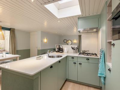 Moderní, světlá kuchyně se zelenými skříňkami a kuchyňským ostrůvkem v rekreačním domě.