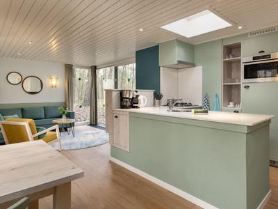 Moderní obývací pokoj a kuchyň s zeleným nábytkem a spoustou denního světla.