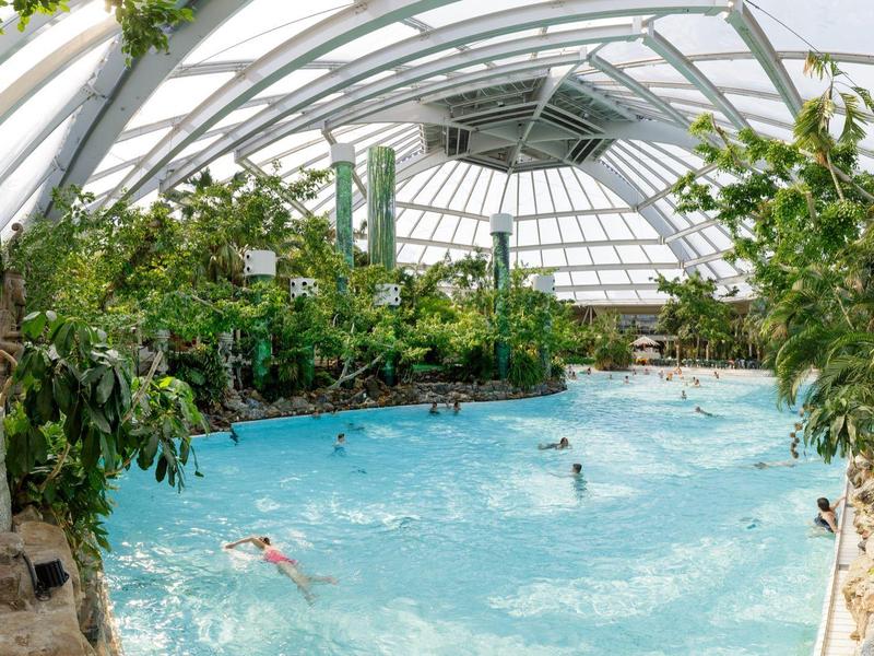 Děti sjíždějí společně vodní skluzavku v tropickém prostředí.