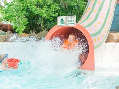 Kinder spielen und rutschen in einem Wasserpark mit Wasserrutsche und Pool.