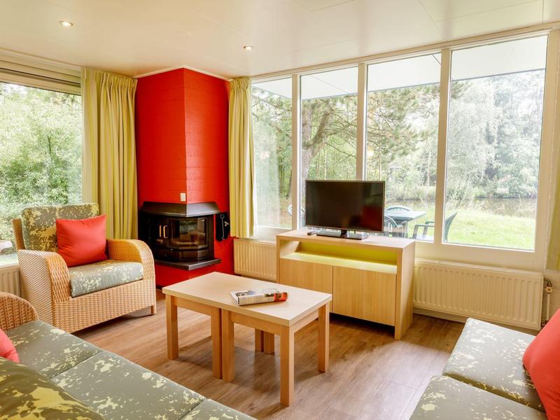 Jasny salon z kominkiem, dużym oknem i wygodnymi miejscami do siedzenia w ciepłych kolorach.