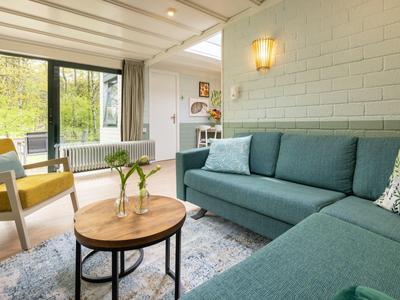 Soggiorno accogliente con divano angolare blu, tavolino in legno e vista sul giardino.