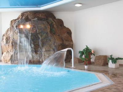 Basen kryty z wodospadami i roślinami w relaksującej hotelowej atmosferze