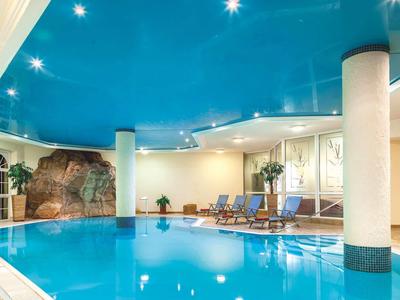 Innenpool mit blauem Dach, Felsenwand und Liegestühlen in einem Hotel.